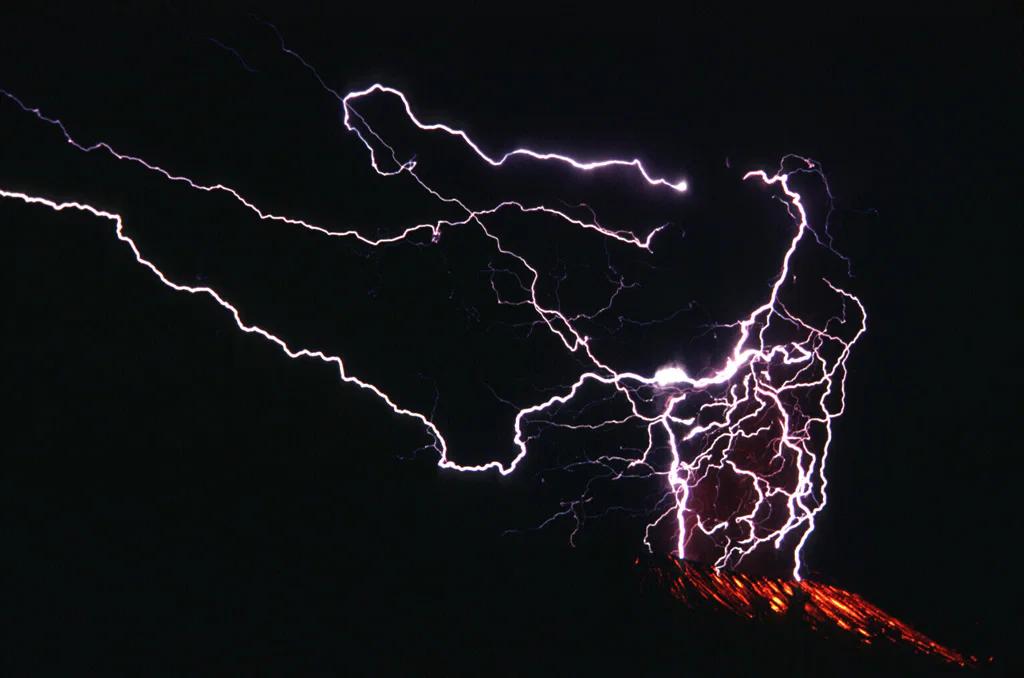 Forks of lightning spread across a dark volcanic plume above glowing ejecta at Galunggung.