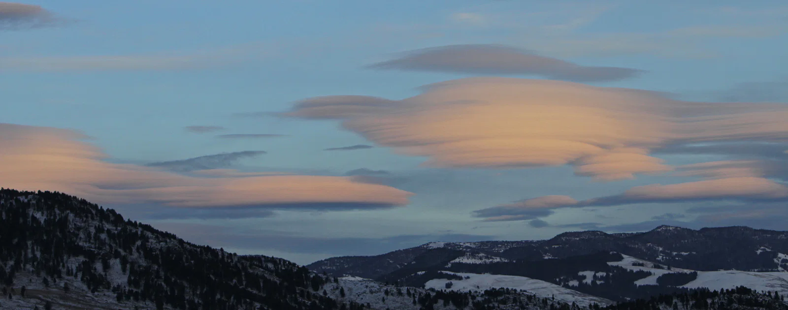 Layered lenticular clouds above rolling hills in Yellowstone.